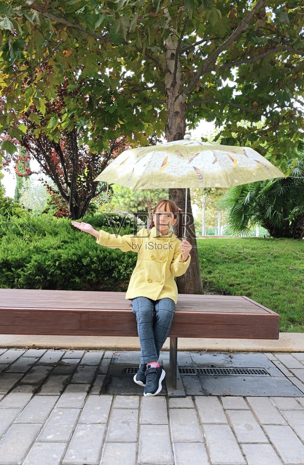 公园里拿着雨伞的小女孩照片摄影图片
