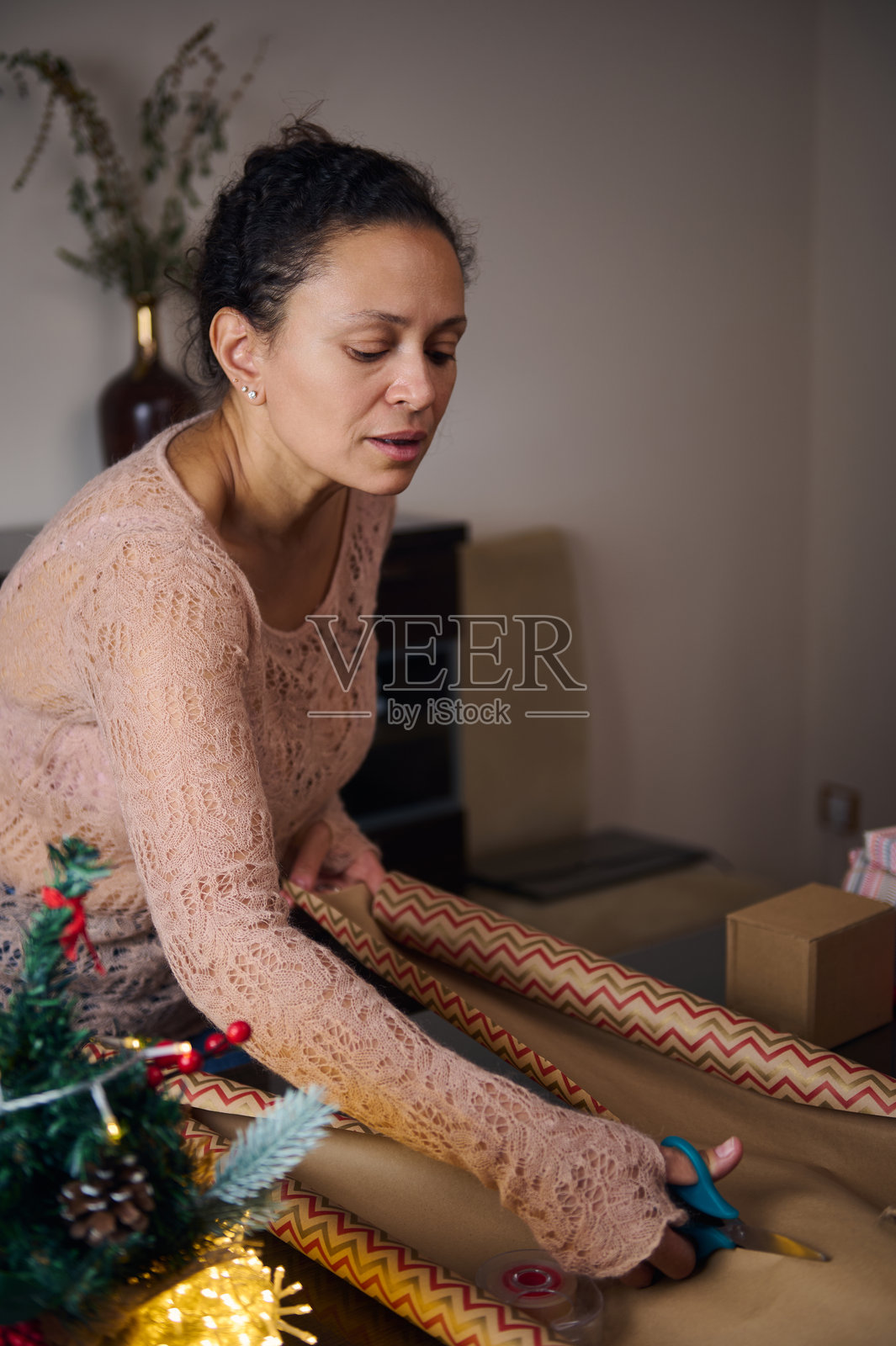 女人坐在节日桌旁包裹圣诞礼物照片摄影图片
