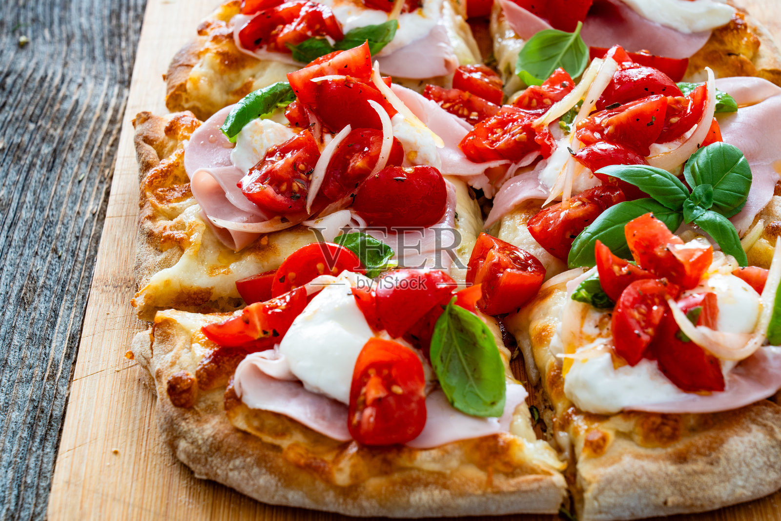 罗马披萨,上面有熟火腿、布拉塔奶酪和蔬菜,放在木桌上照片摄影图片