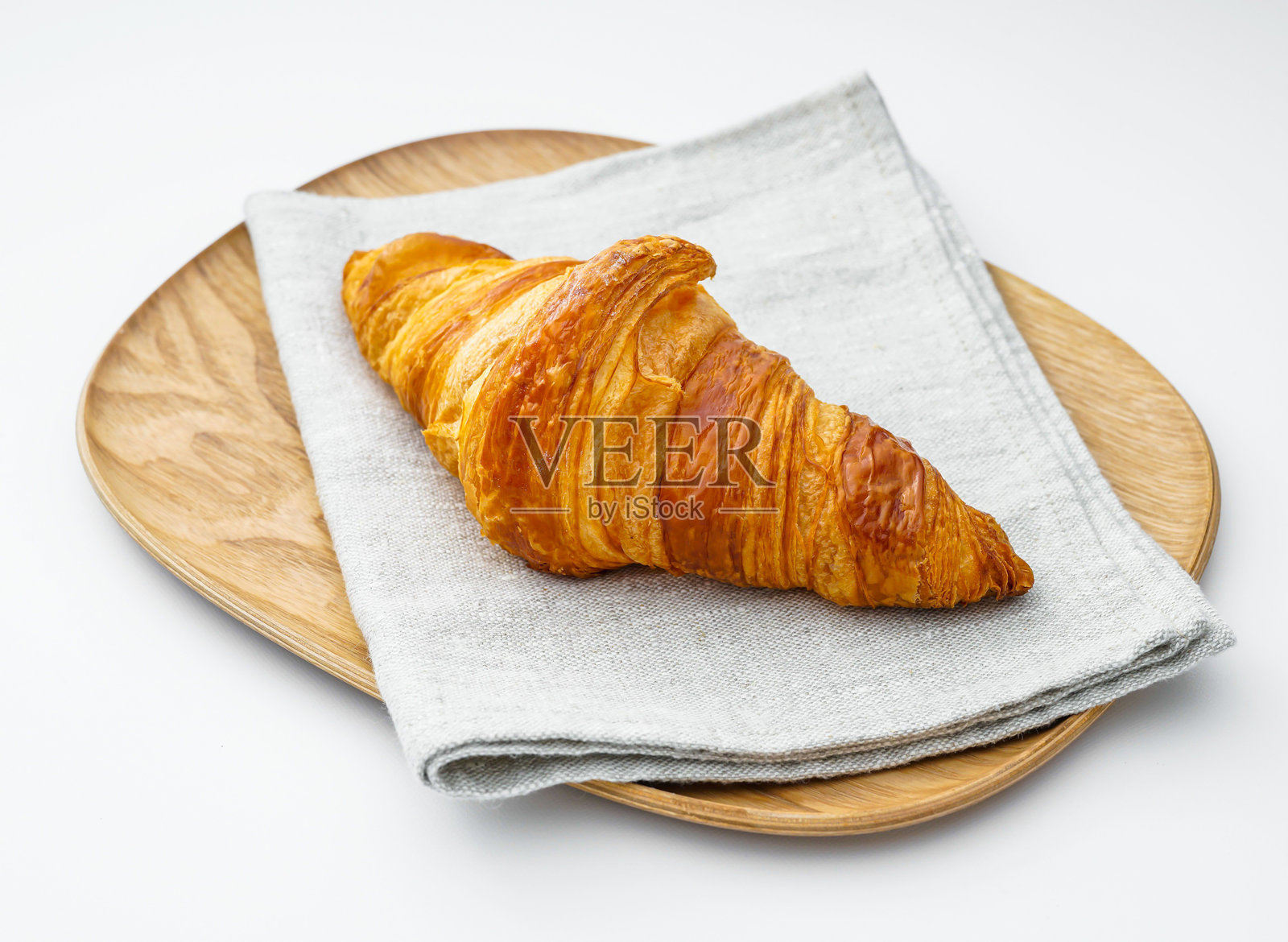 木盘和餐巾上的金黄色烤可颂,酥脆的法式糕点,背景为白色照片摄影图片