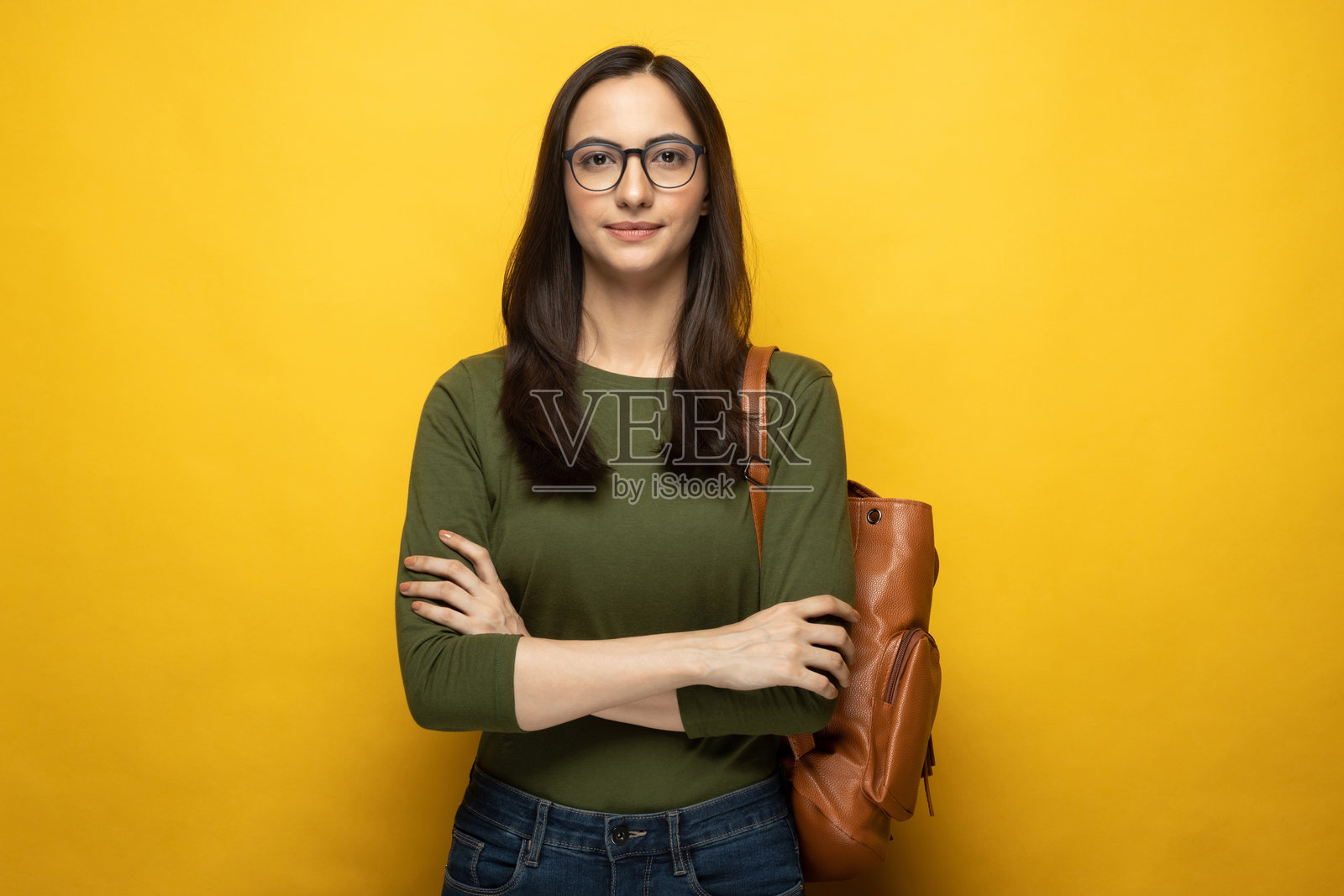 照片:漂亮年轻的女学生,背着包,在黄色背景下独立照片摄影图片