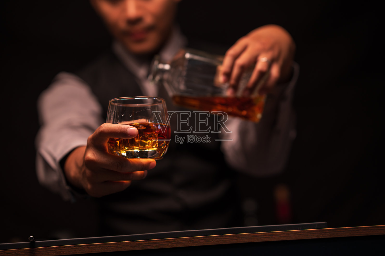 调酒师在餐厅里向杯中倒威士忌照片摄影图片