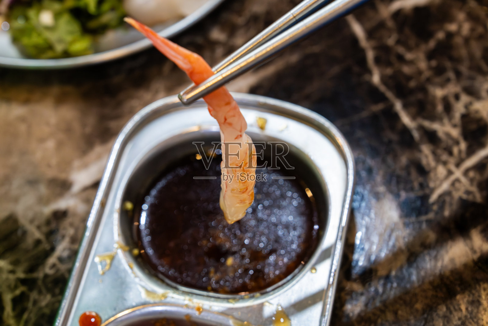 将虾生鱼片蘸入酱油照片摄影图片