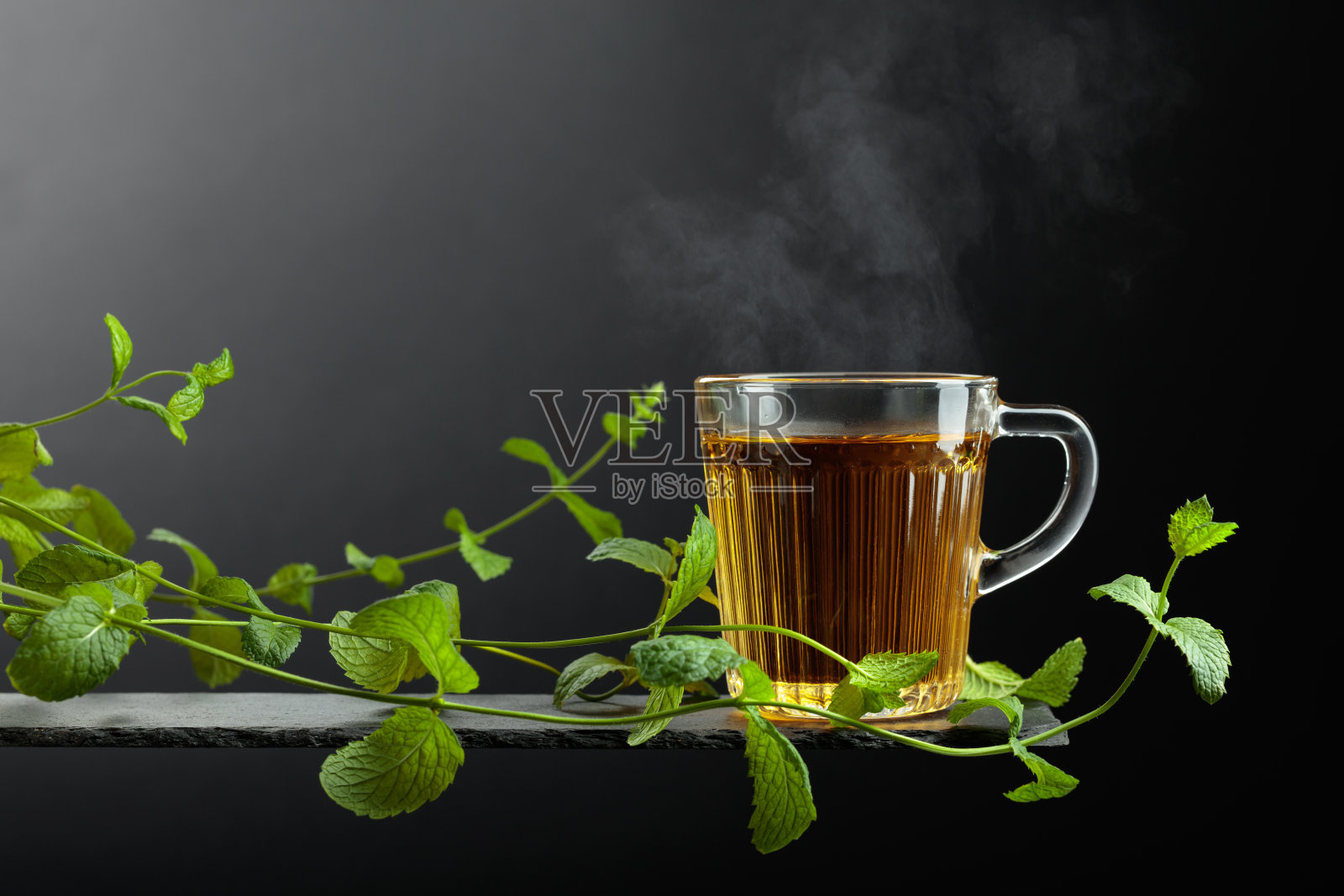 一杯薄荷茶和新鲜的薄荷枝。照片摄影图片