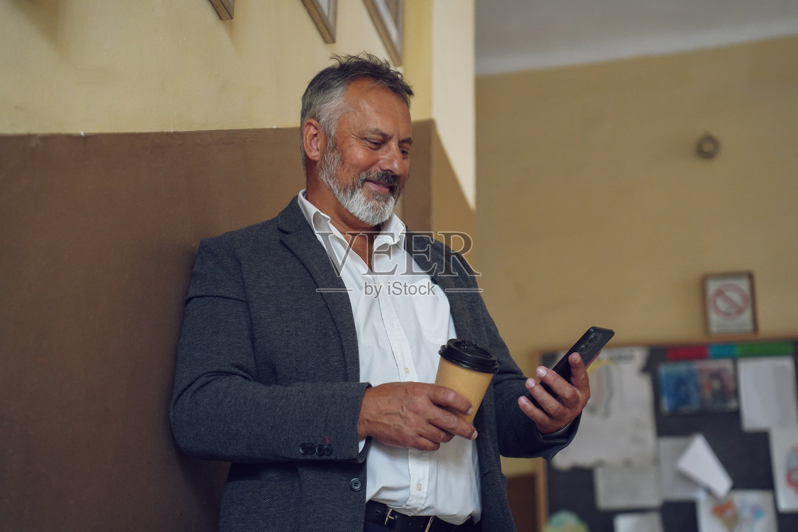 资深教师在学校走廊享受咖啡休息时间照片摄影图片