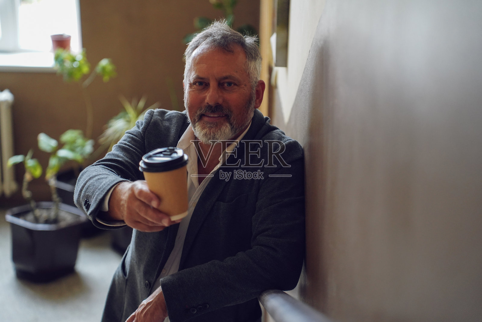 年长的老师在学校走廊享受咖啡休息时间照片摄影图片