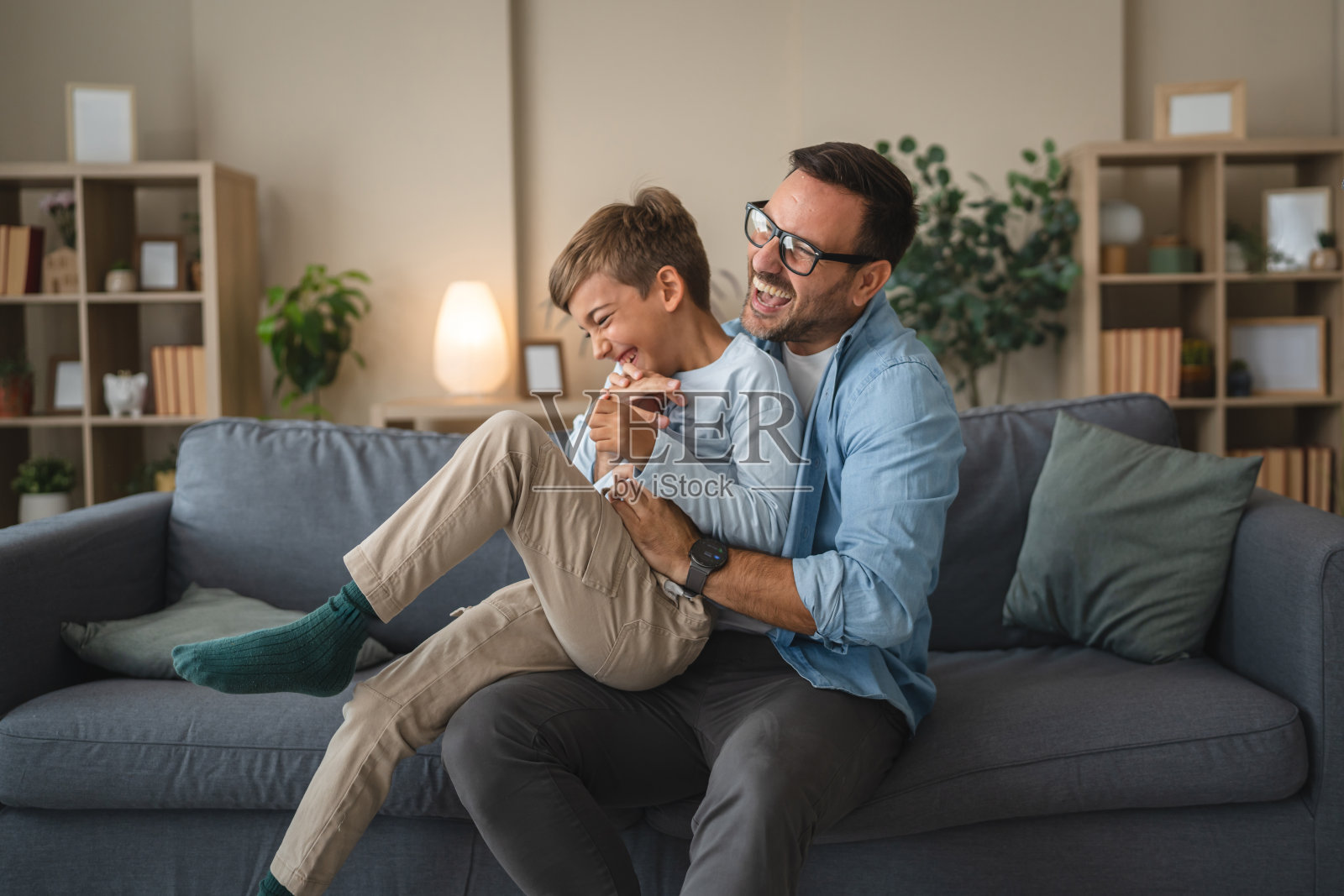 父子俩在沙发上开心地互相打闹嬉戏照片摄影图片