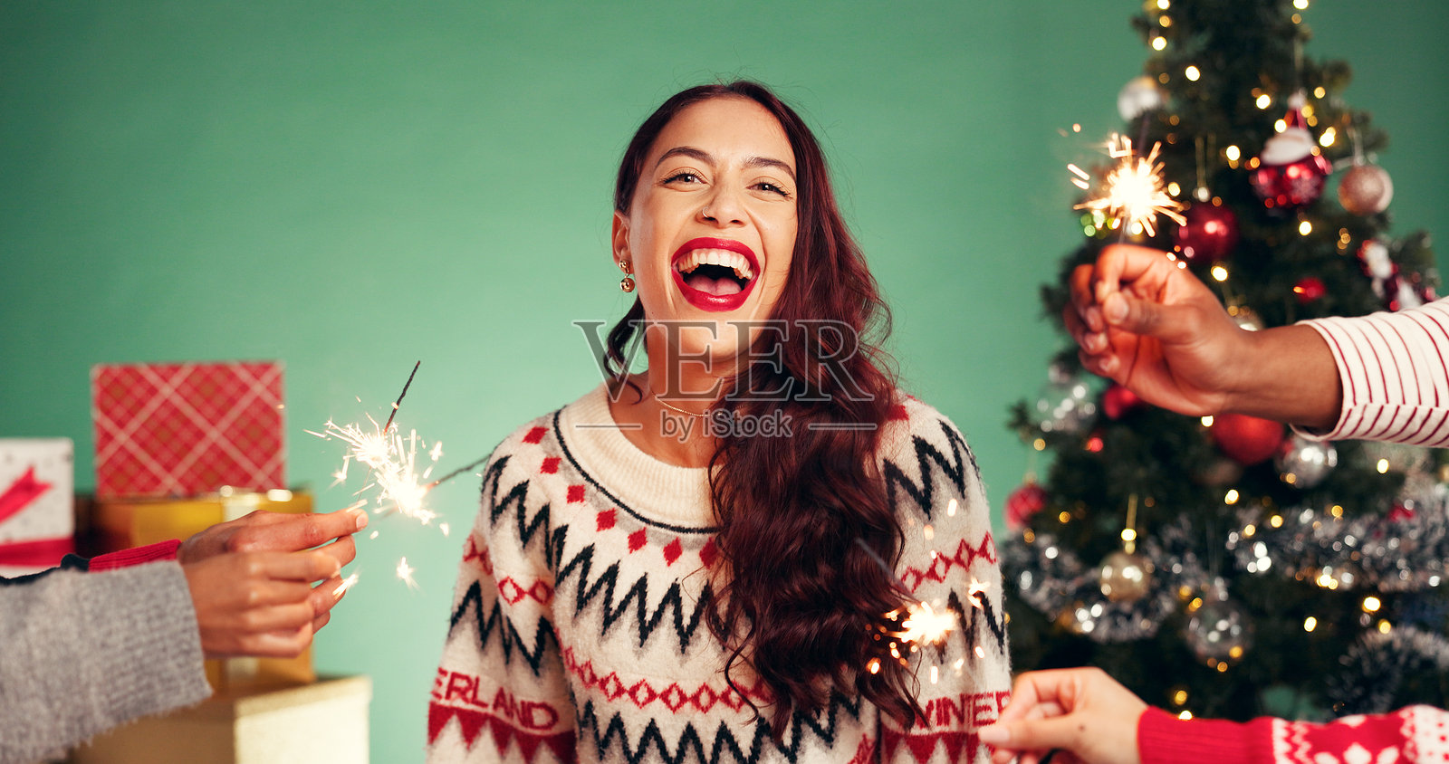 圣诞节,工作室里,一个兴奋的女人手里拿着仙女棒,背景是绿色的,充满节日气氛。快乐的女孩,圣诞节和烟花,用于节日庆祝,有趣的肖像或与朋友聚会时的笑声。照片摄影图片