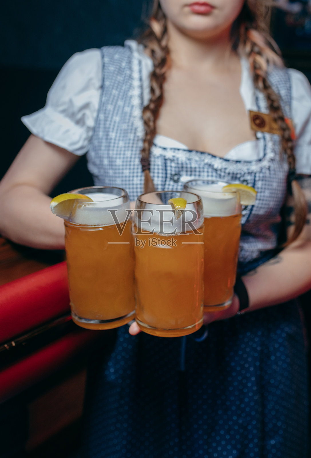 酒吧里,年轻的女服务员拿着啤酒,特写镜头。照片摄影图片