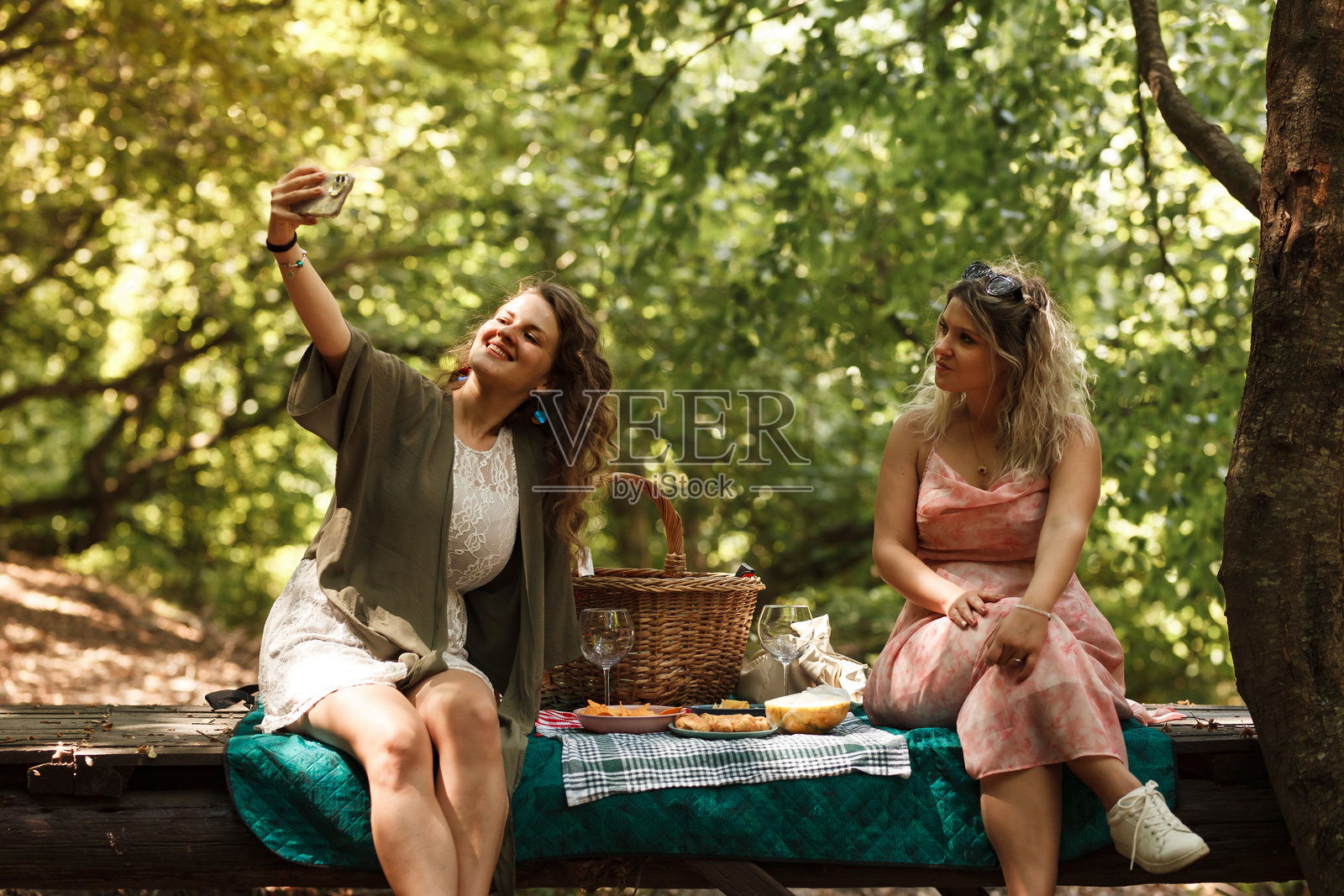 阳光明媚的午后,朋友们在绿意盎然的森林空地上享受野餐,在大自然的怀抱中记录美好回忆。照片摄影图片