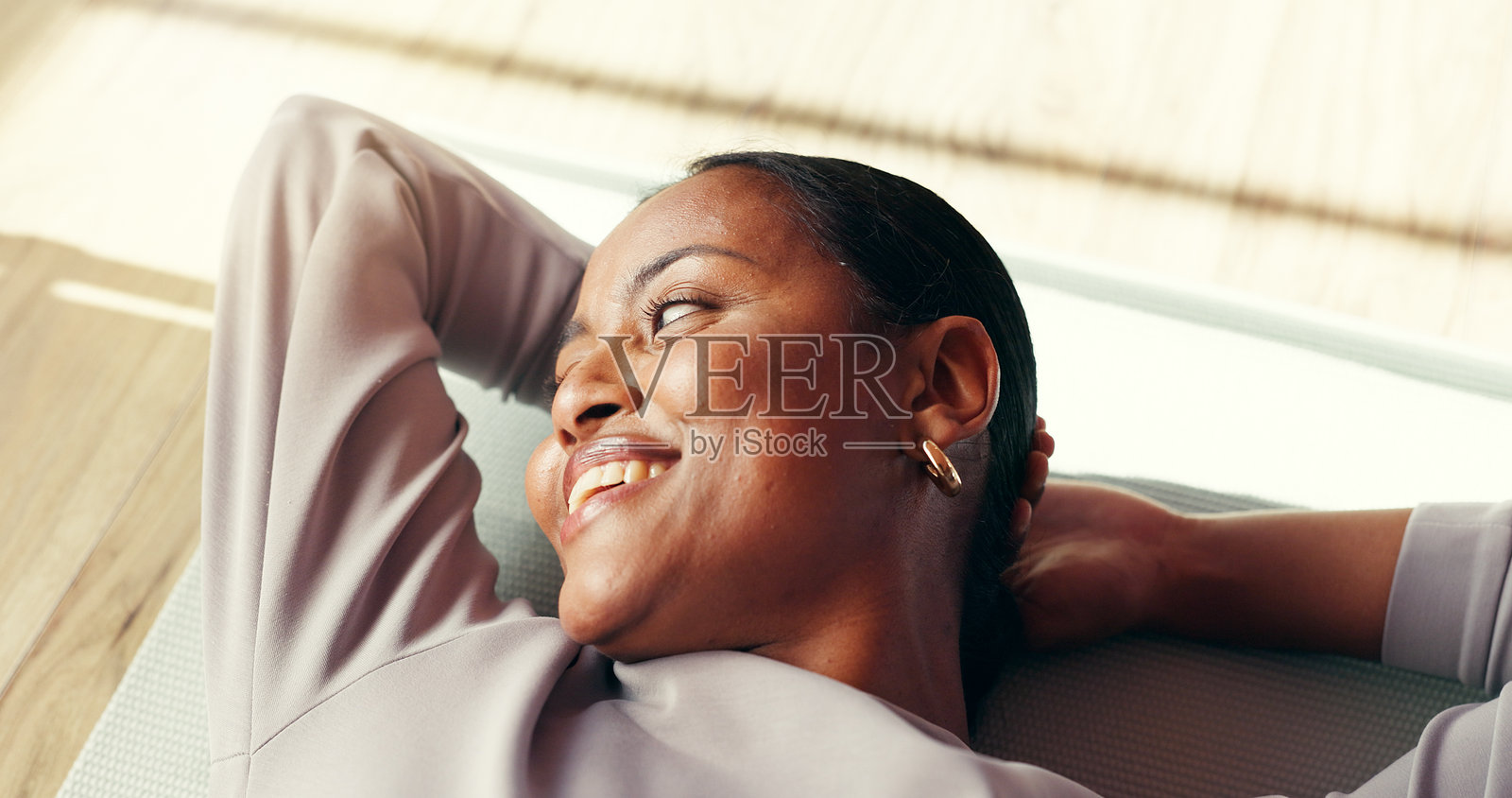 健身房,瑜伽垫上的女人,正在休息和微笑,思考着健康或普拉提,或者只是有些疲惫。在背景中,一位黑人女性在健身房休息,脸上带着满足的笑容,似乎是完成了锻炼,享受着健康和健身的成果。照片摄影图片