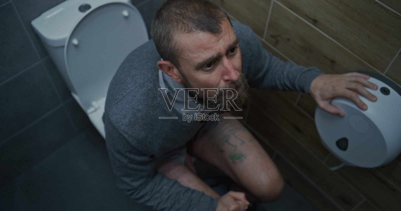 腹泻时坐在马桶上表情痛苦的男人照片摄影图片