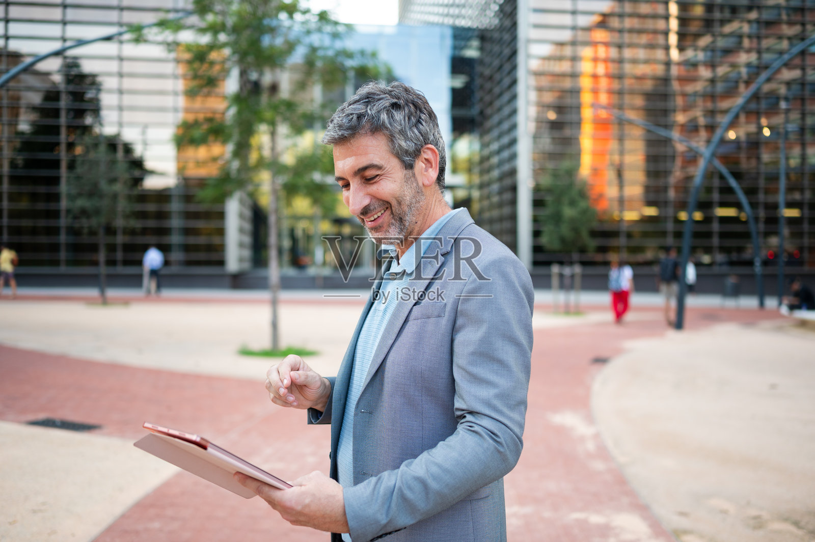 成熟的成年男子在户外使用数码平板电脑微笑照片摄影图片
