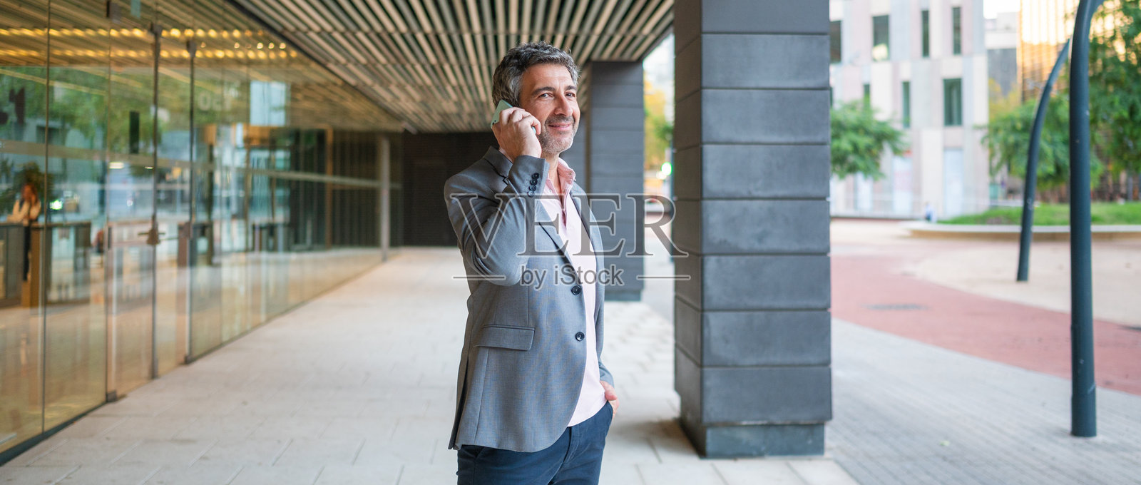 商务人士在市区边打电话边微笑照片摄影图片