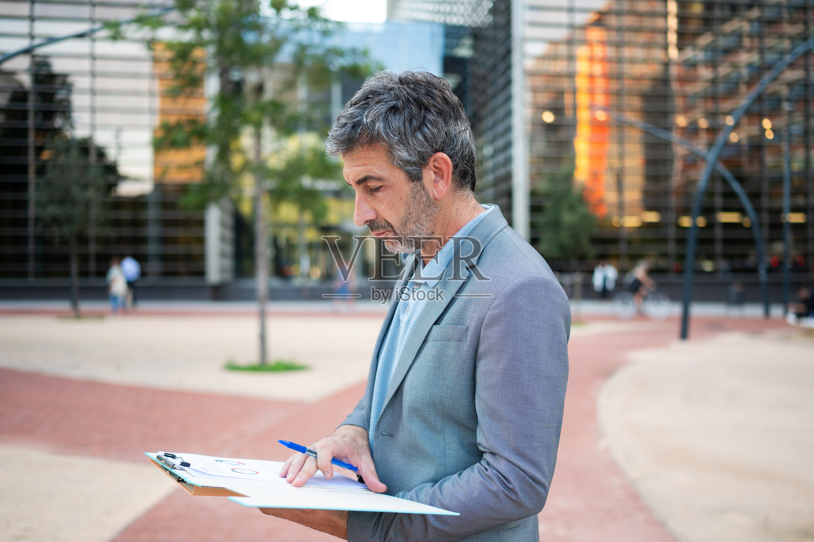 成熟的成年男子在户外使用剪贴板审阅文件照片摄影图片
