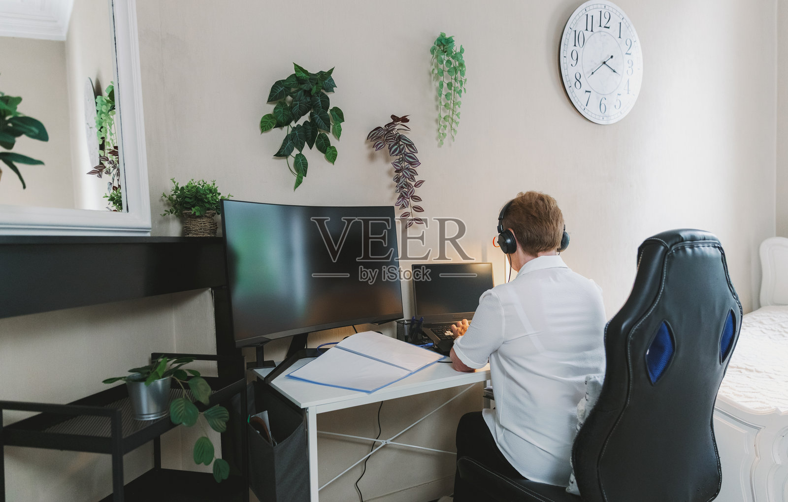 一位戴着耳机的年长女性正在使用笔记本电脑。照片摄影图片