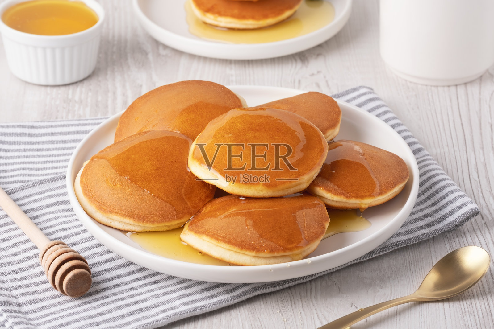 美味蓬松的煎饼淋上糖浆,摆放在白盘中作为早餐。照片摄影图片