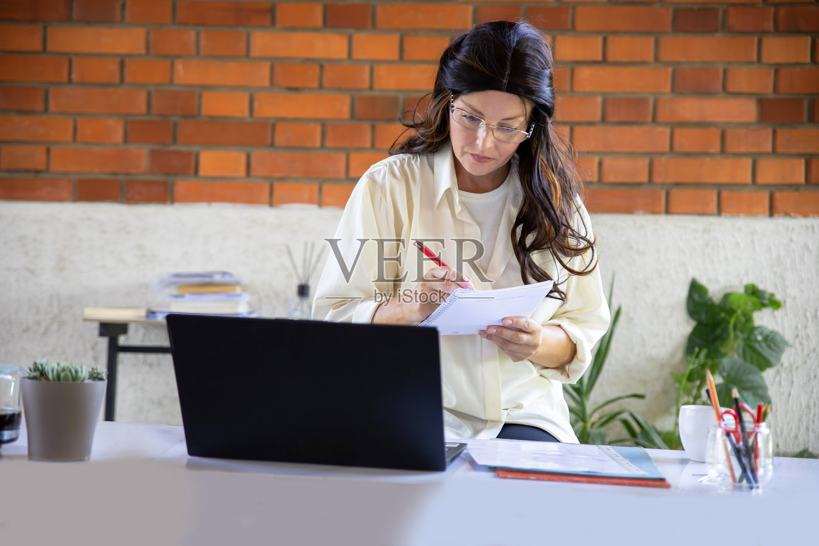 一位女士在现代办公室环境中,使用笔记本电脑处理文件。照片摄影图片