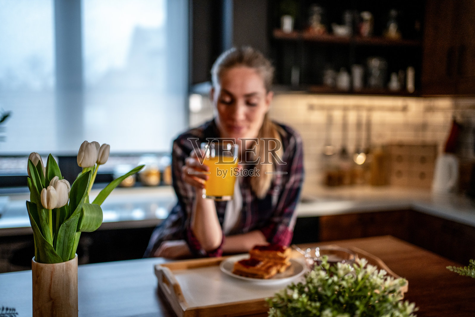 女人在舒适的厨房早餐时喝橙汁照片摄影图片