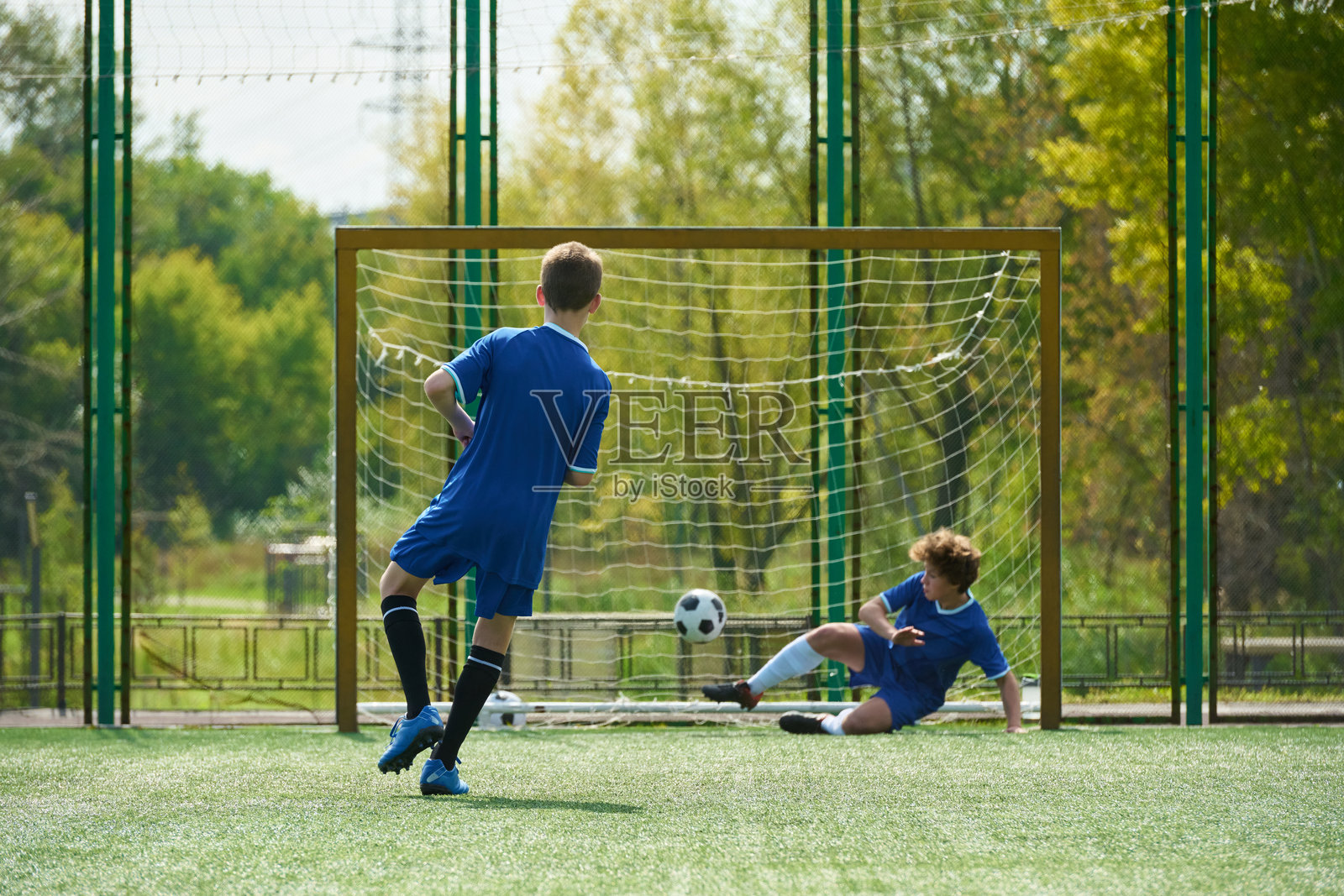 一名少年正带球射门,守门员扑救照片摄影图片