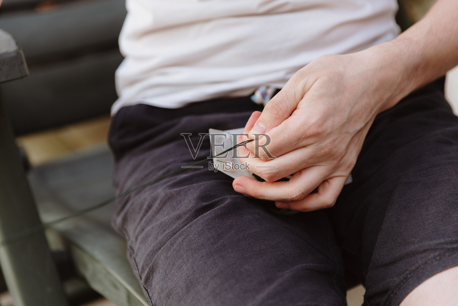 一个人在花园小屋上安装灯串,正在剪断电线。照片摄影图片