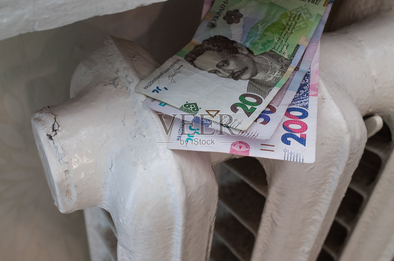 乌克兰格里夫纳纸币放在家用散热器上,象征着高昂的供暖费用。支付水电费。能源价格上涨。照片摄影图片