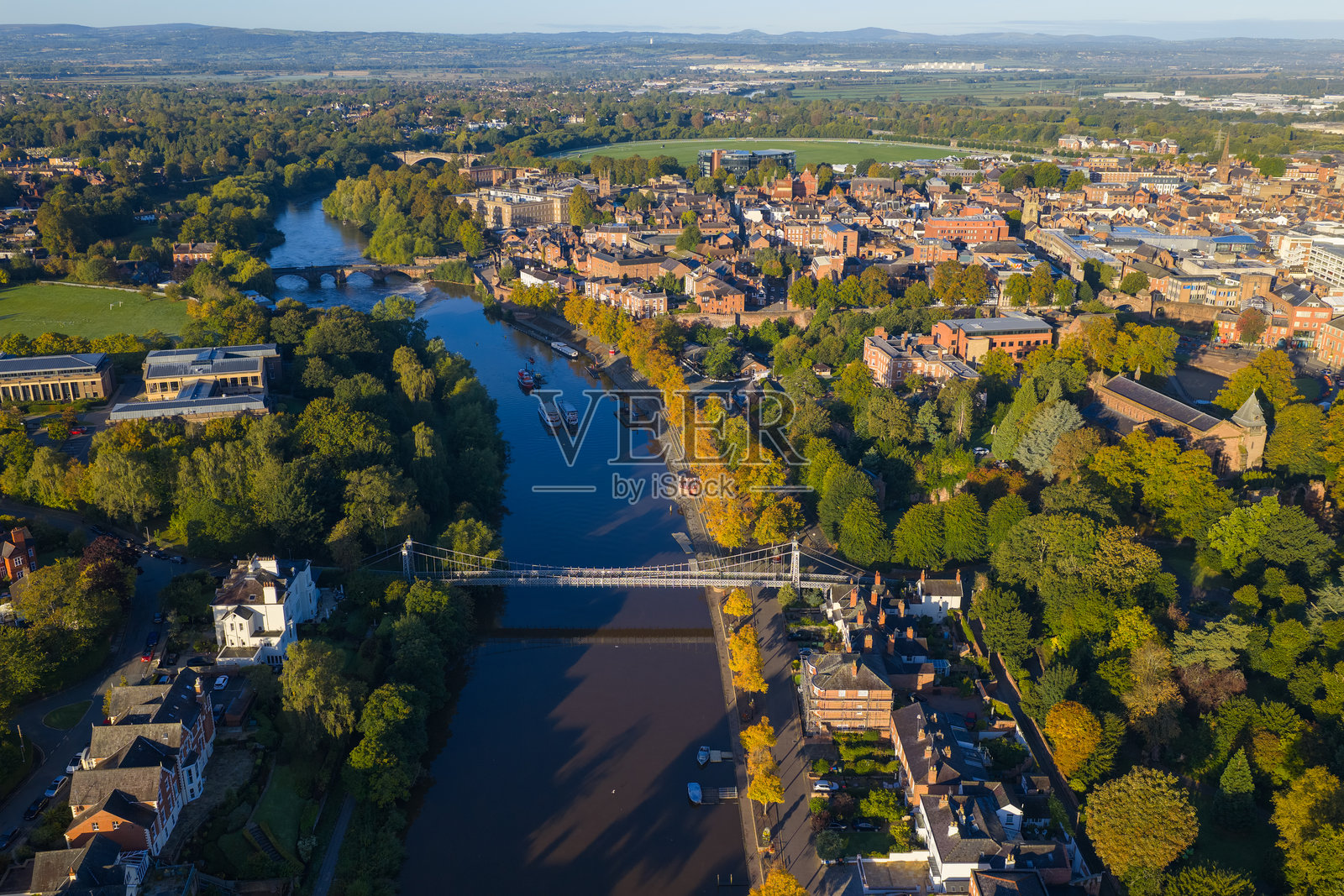 切斯特悬索桥跨越迪伊河的鸟瞰图,桥上有船只,远处是城市景观。照片摄影图片