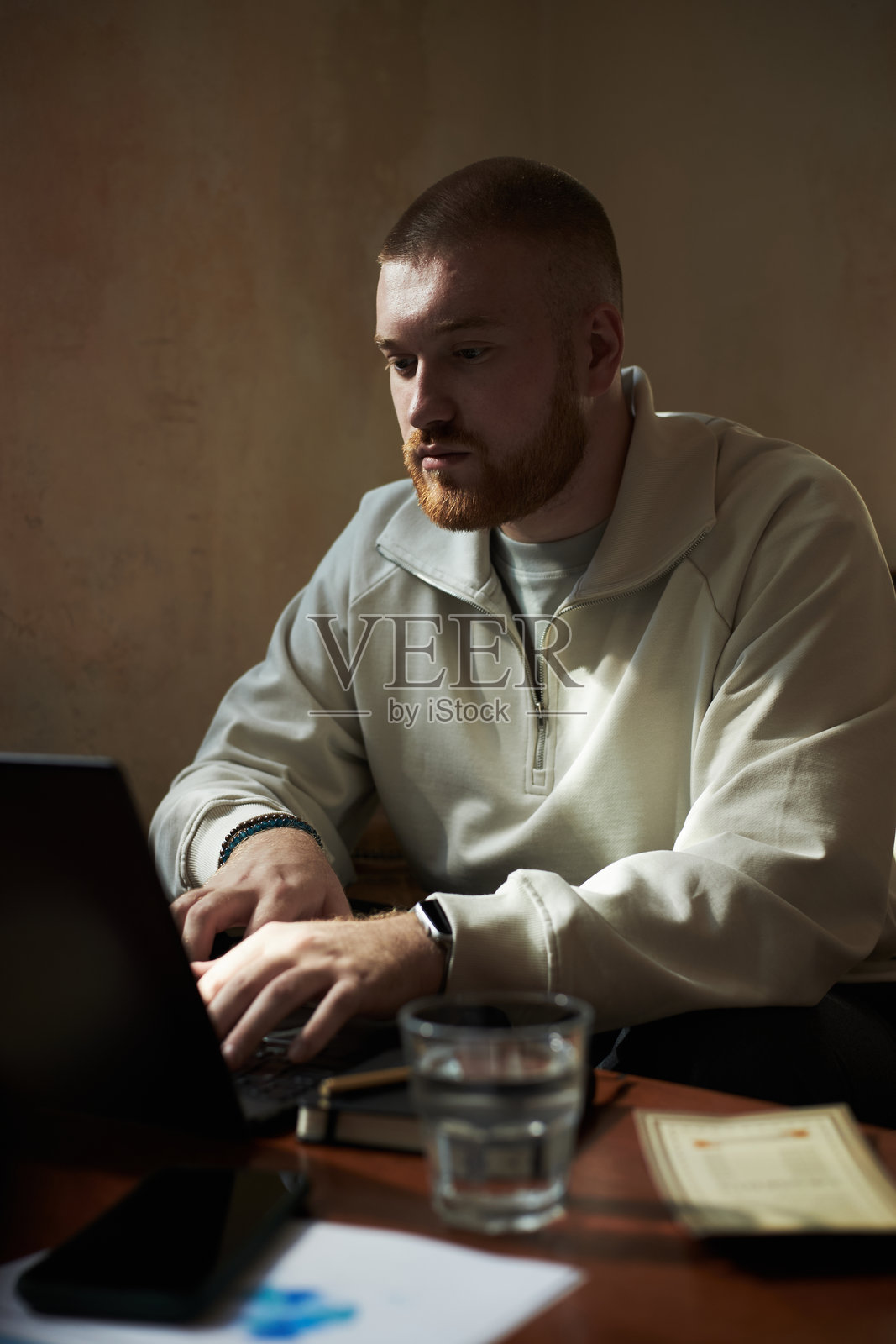 一名白人年轻男性在自然光下于书桌前使用笔记本电脑工作照片摄影图片