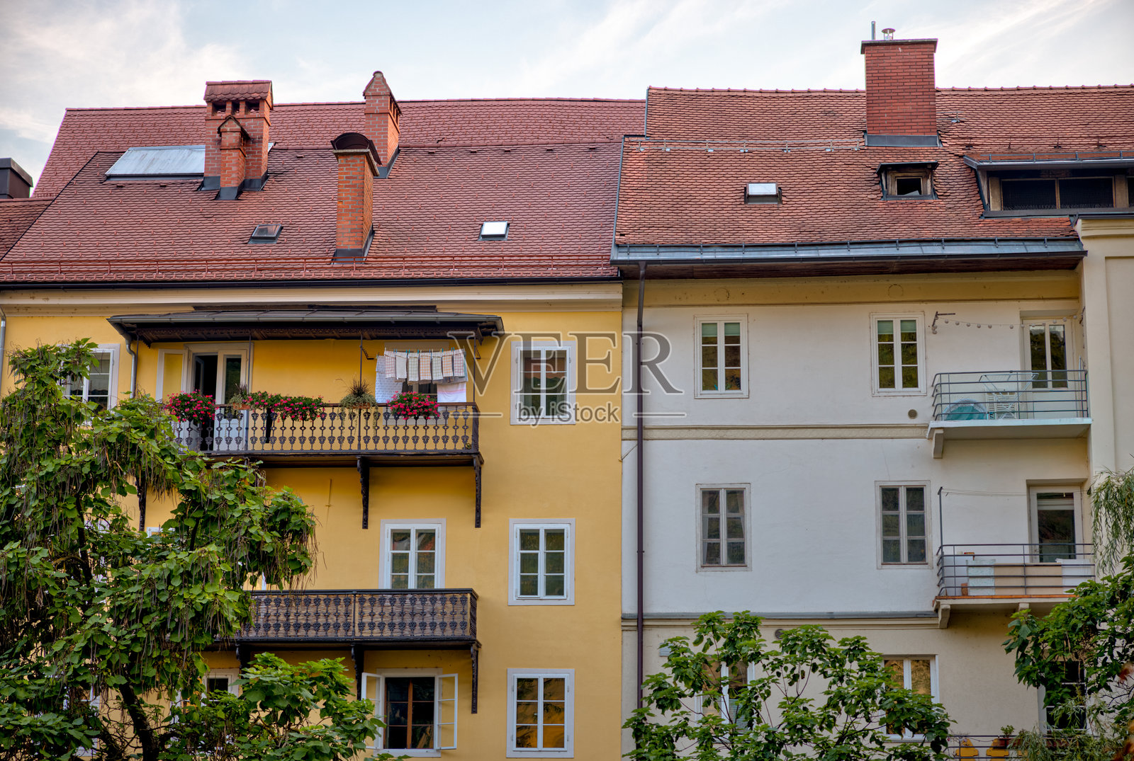 温馨柔和色调的邻近公寓楼,配有阳台和屋顶烟囱,构成一幅宁静的住宅景象。照片摄影图片