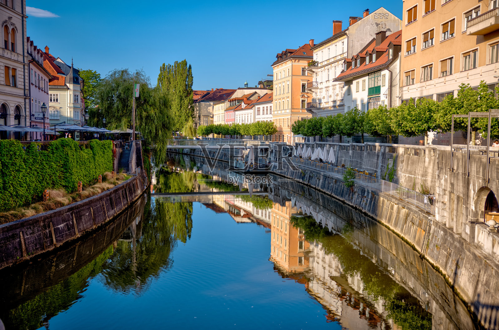 卢布尔雅那河穿过卢布尔雅那历史中心的美景,两岸绿树成荫,遍布咖啡馆和迷人的河畔建筑。照片摄影图片