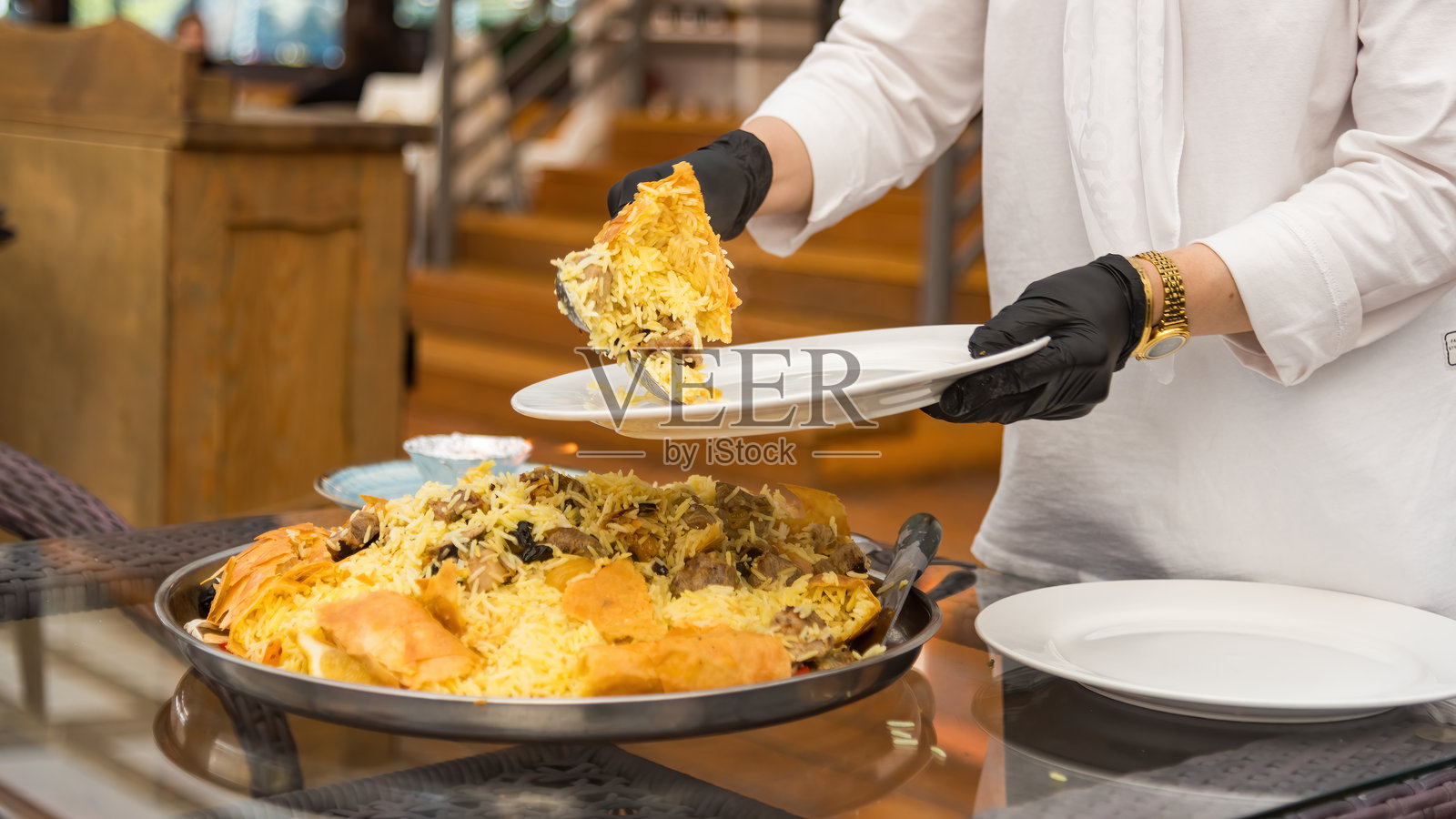 服务员端出刚烹制好的沙皇抓饭。照片摄影图片