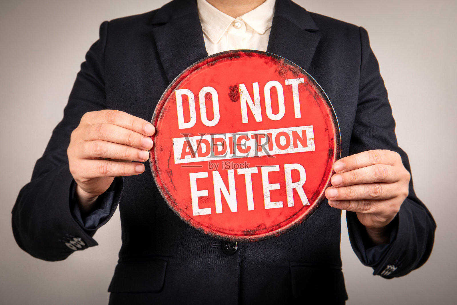 女商人举着红色的圆形警告标志,上面写着“禁止成瘾,禁止进入”,概念涉及禁止、意识、危险、心理学、社会问题和风险沟通。照片摄影图片