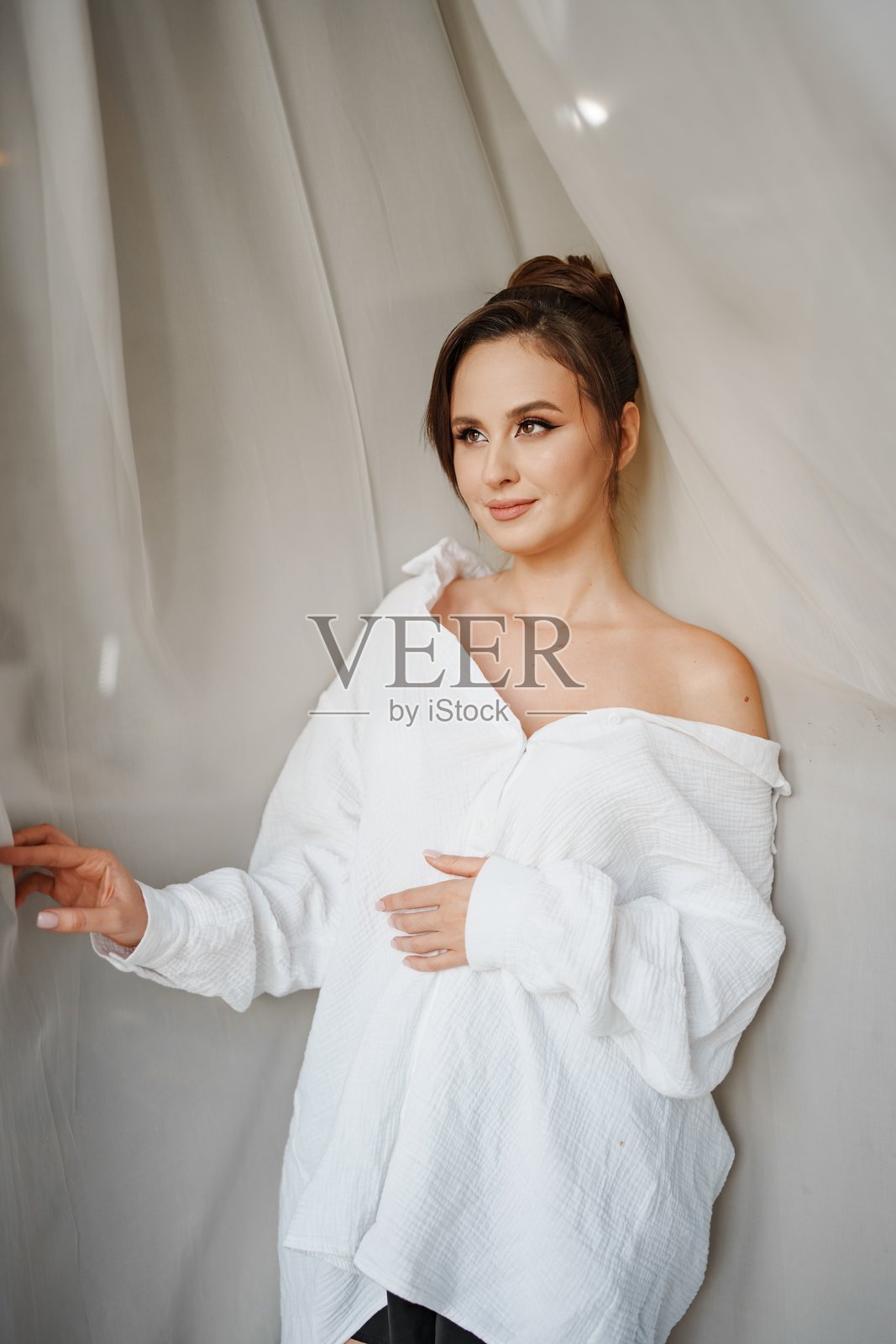 身穿白色露肩衬衫的年轻女子,在窗帘旁,美丽而温柔照片摄影图片