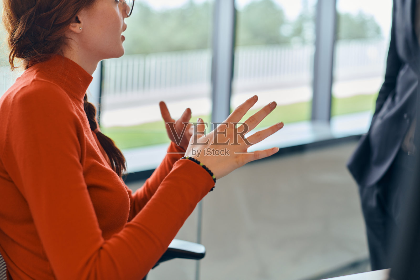 在一家现代创业公司办公室里,一位橙色头发的现代女商人正与她的总监讨论业务挑战,这反映了企业界解决问题时的协作和动态特性。照片摄影图片