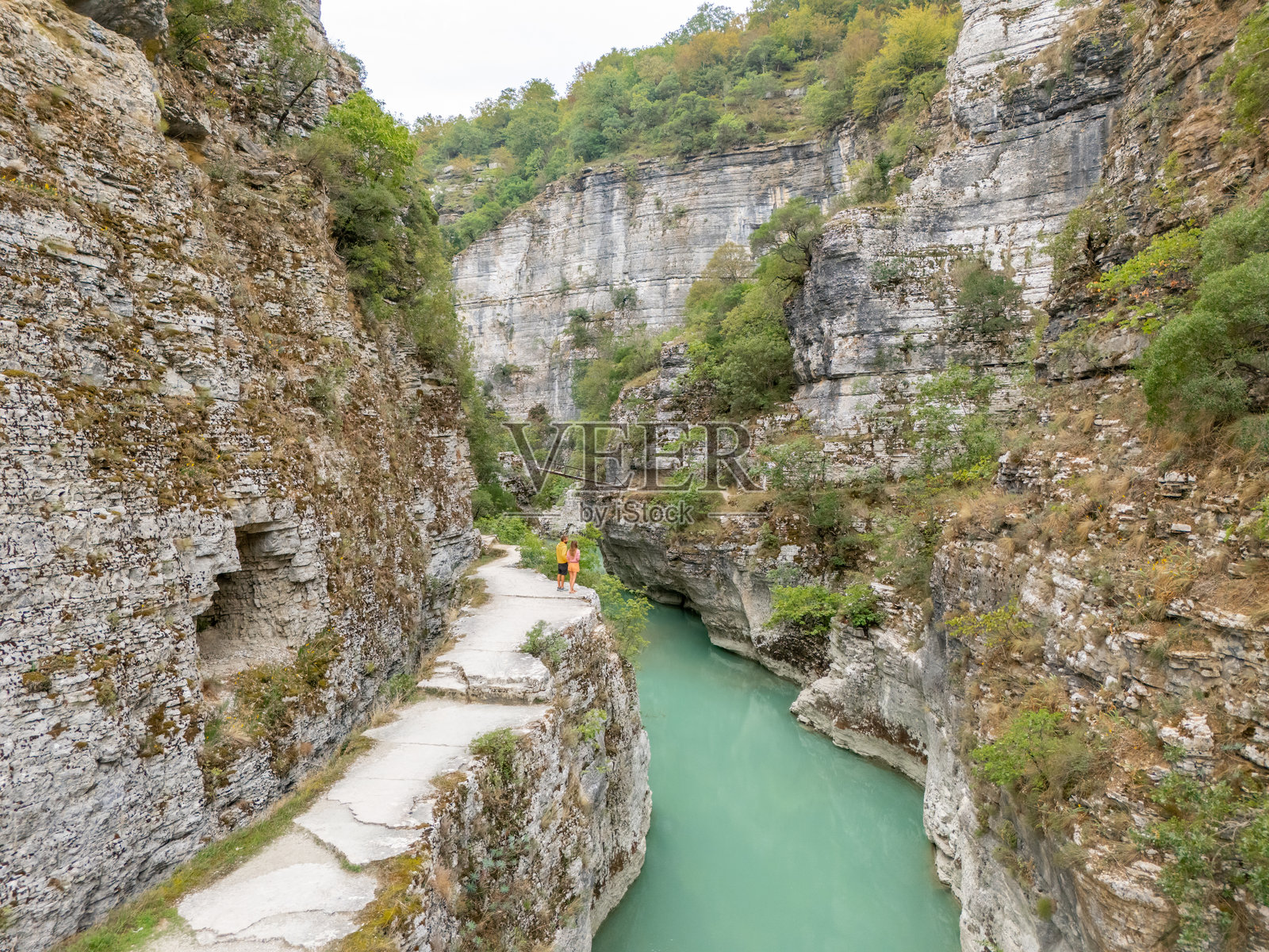 情侣站在悬崖上俯瞰峡谷河流照片摄影图片