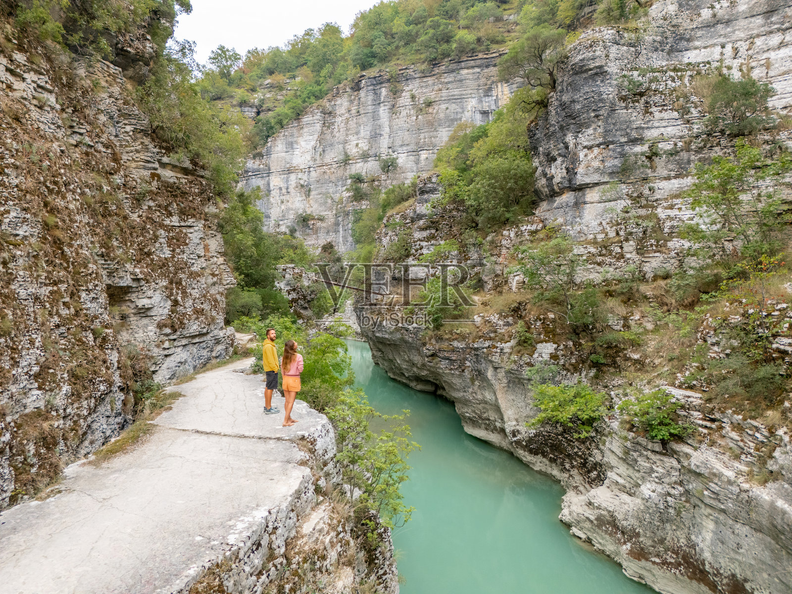 一对情侣站在悬崖边俯瞰峡谷河流照片摄影图片