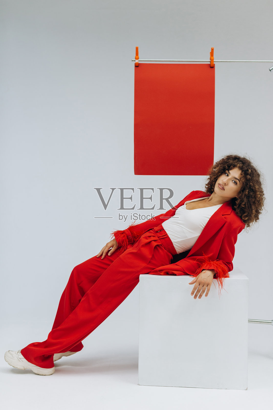 穿着红色套装的卷发年轻女子肖像照片摄影图片