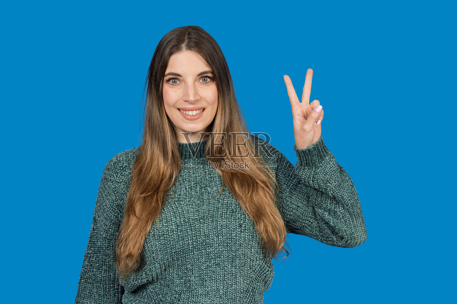 年轻女子微笑着用手比出胜利手势照片摄影图片