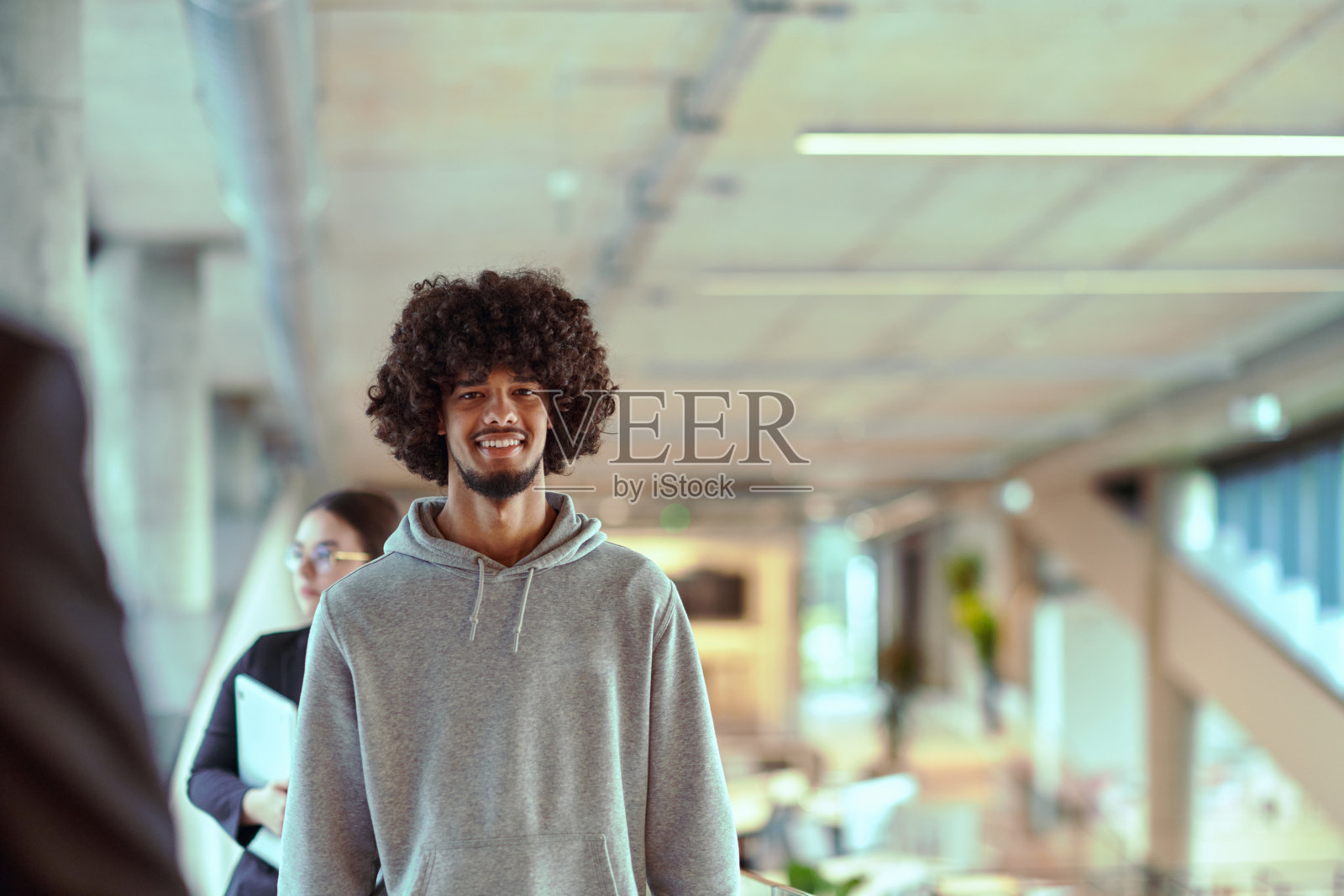 在现代办公环境中,一位年轻的非裔美国企业家正在工作,而在背景中,他敬业的同事们展现了团队合作与协作精神,这正是当代企业成功的精髓。照片摄影图片