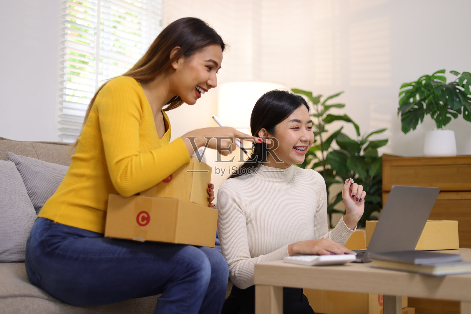 两位年轻亚洲女性正在处理包裹盒,她们在家创业,开展在线购物业务。照片摄影图片