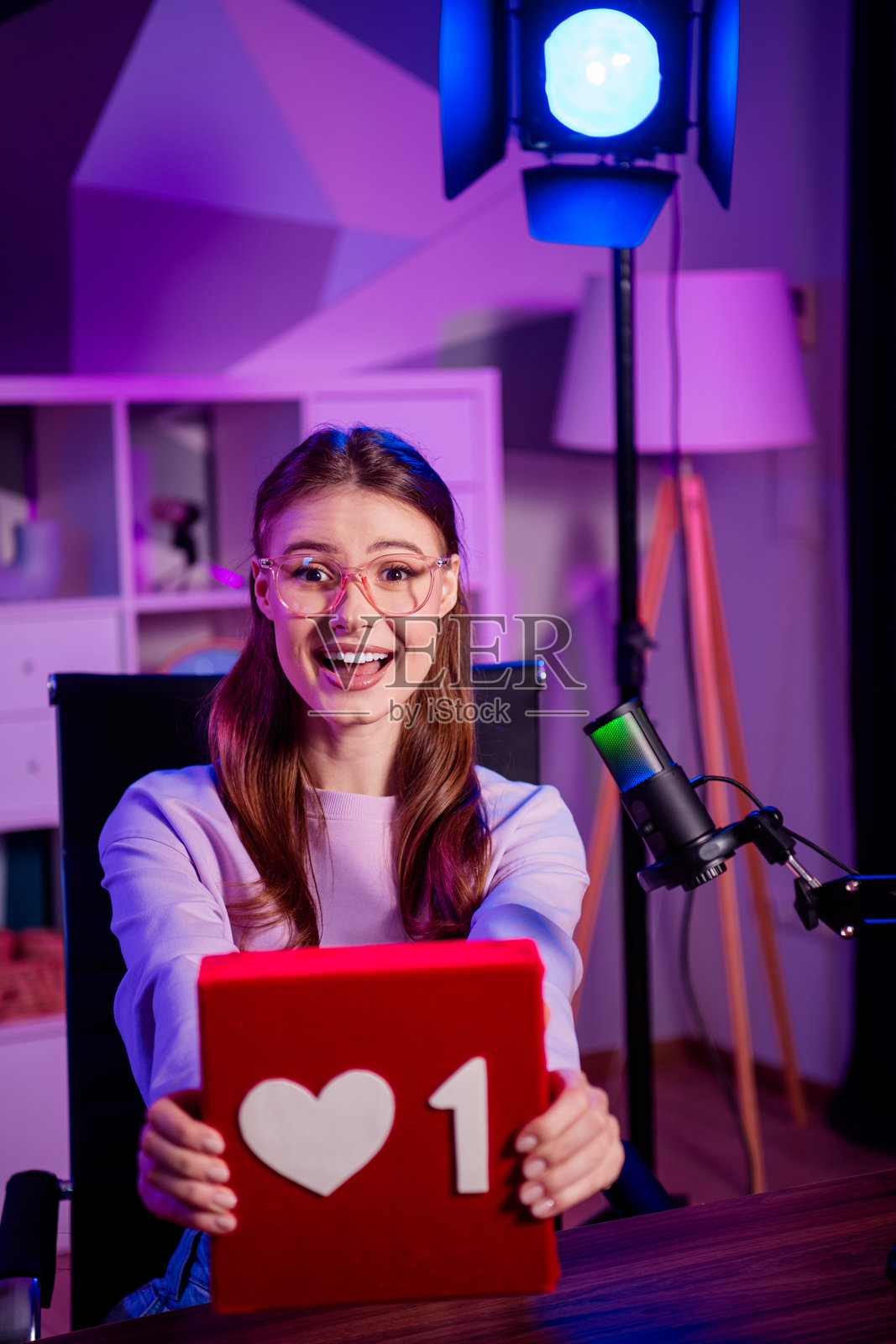 年轻女子居家休闲风格在线直播播客,配有麦克风设备和霓虹灯光照片摄影图片