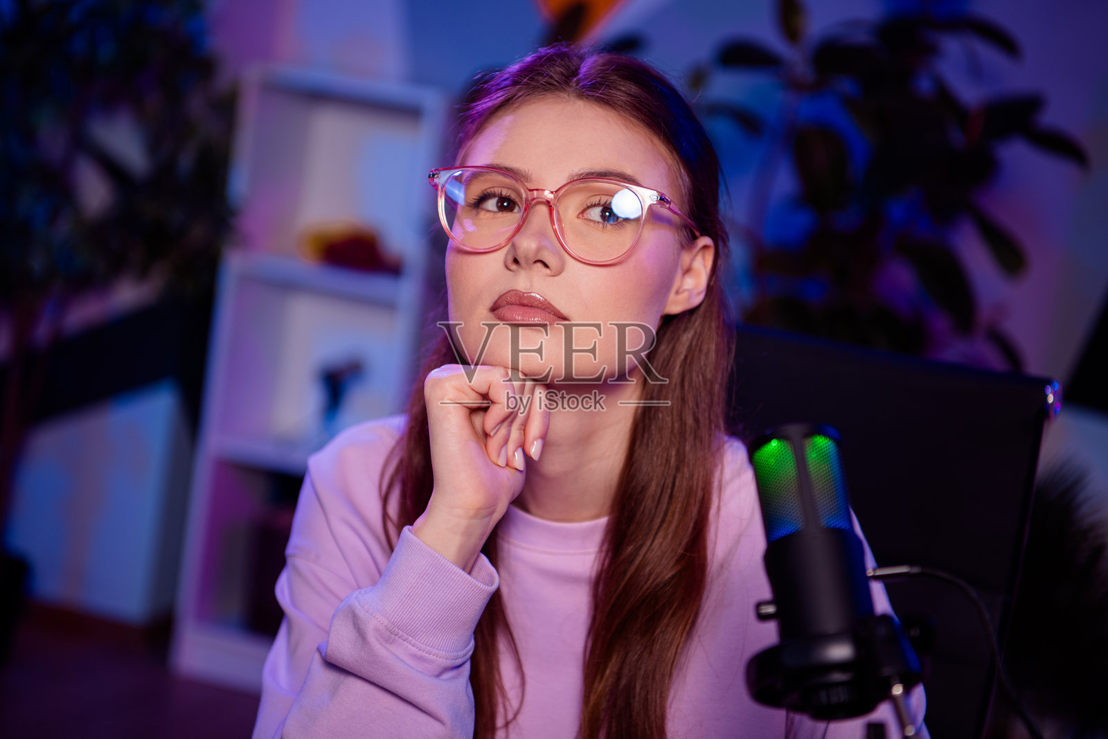 年轻的职业女性在家直播,室内工作室有霓虹灯光,配备麦克风照片摄影图片