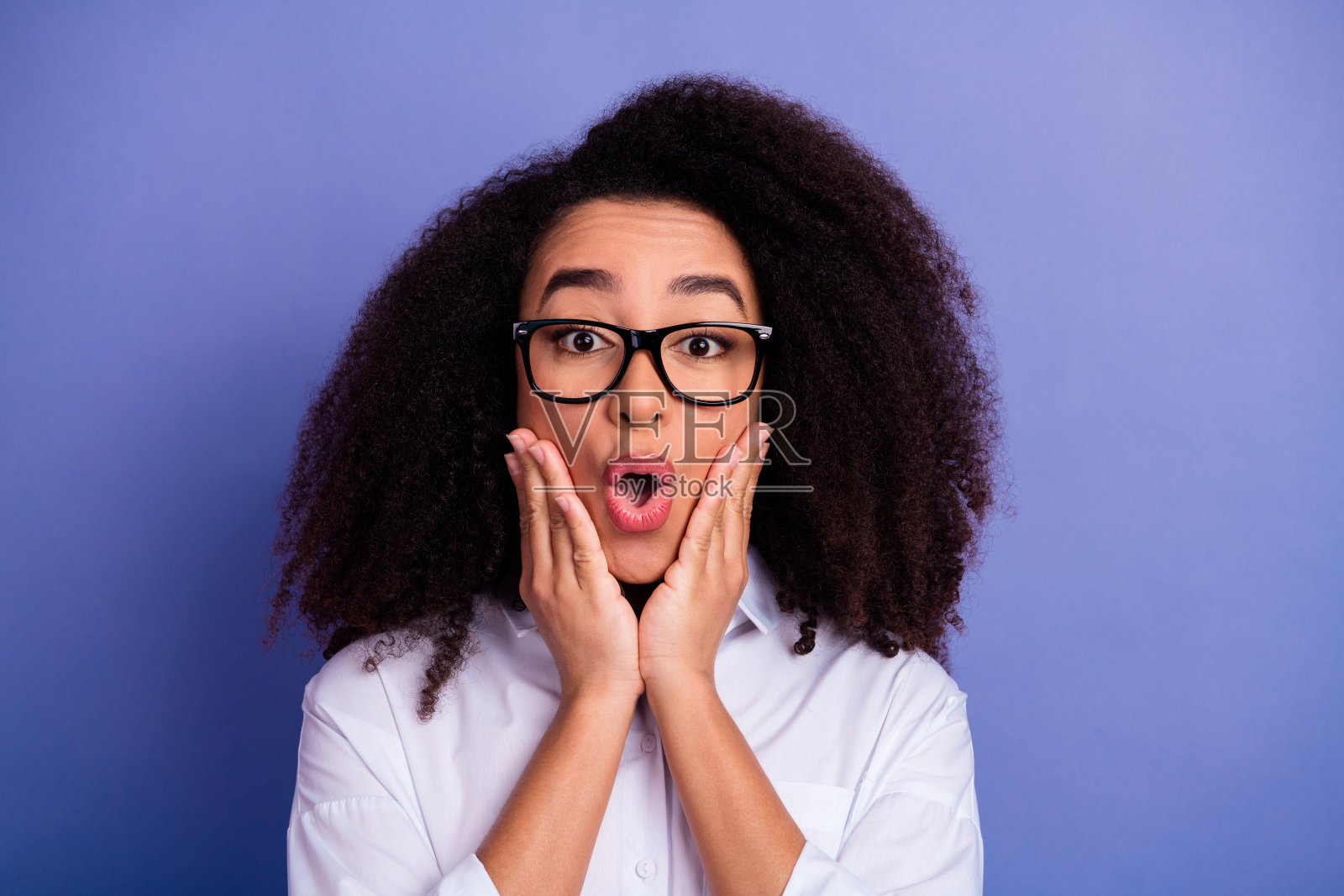 戴眼镜的年轻女子身着正装,在紫色背景前摆姿势,表情惊讶照片摄影图片