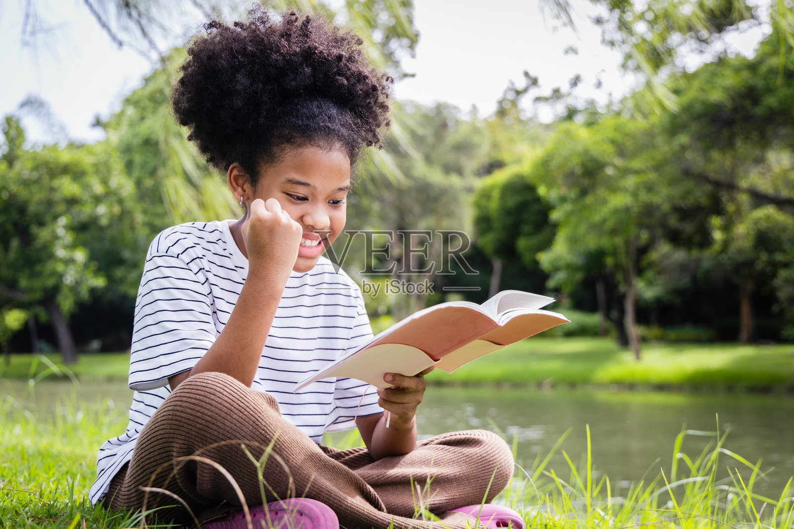年轻女孩在湖边阅读书籍,体现了家庭教育的生活方式,快乐的孩子正在学习。照片摄影图片