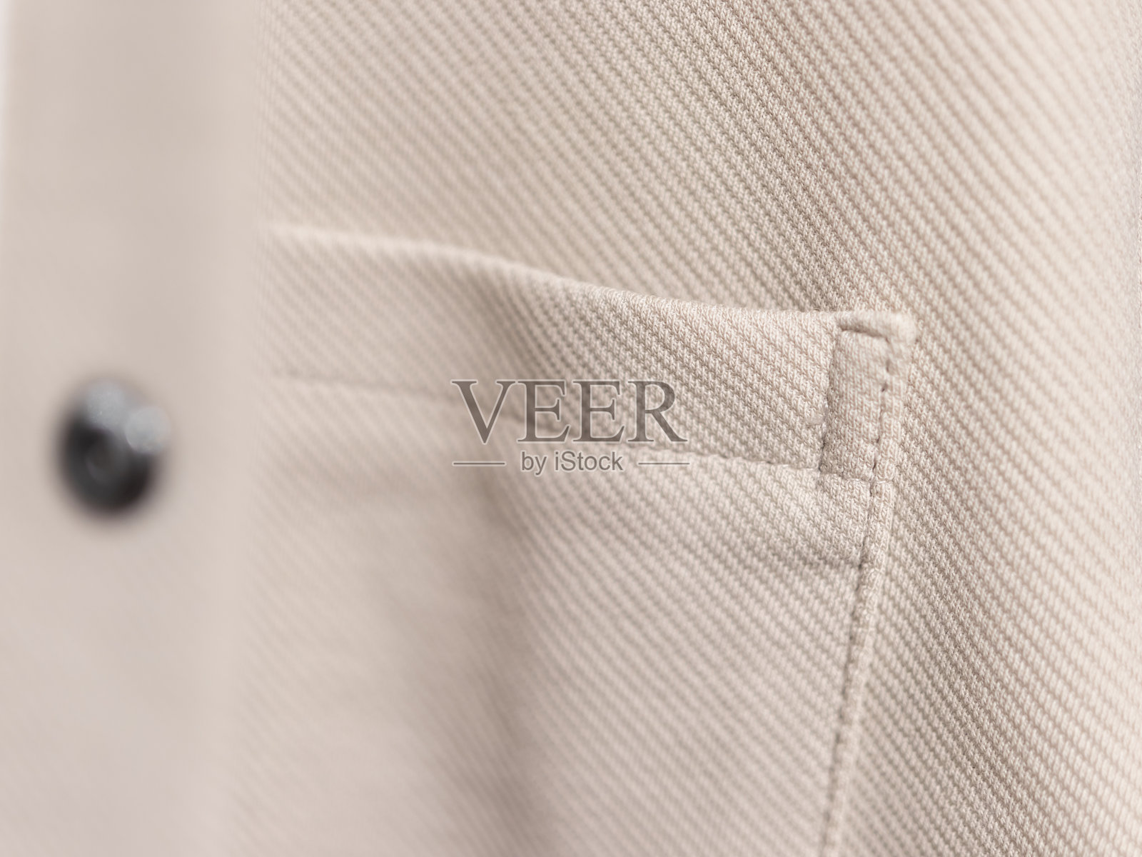 米色斜纹布料纹理和口袋细节的特写,展现出斜向编织、细致的缝线,极简而中性的时尚背景。照片摄影图片