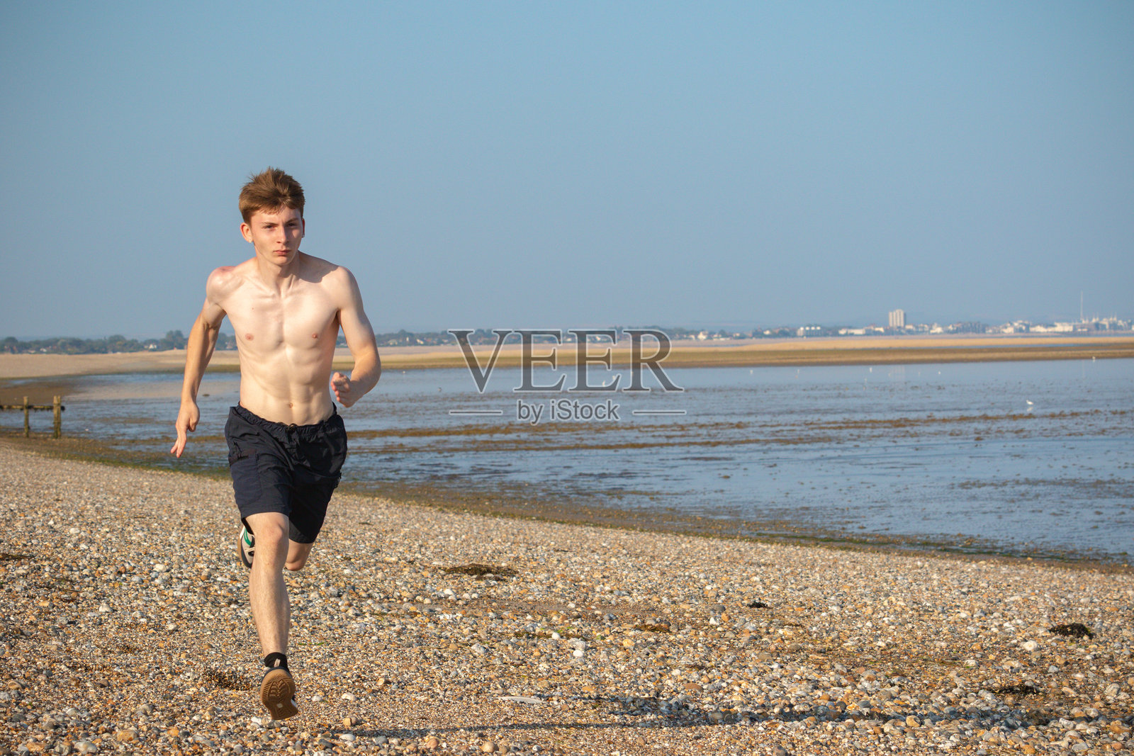 赤膊的少年在海滩上向镜头跑来照片摄影图片