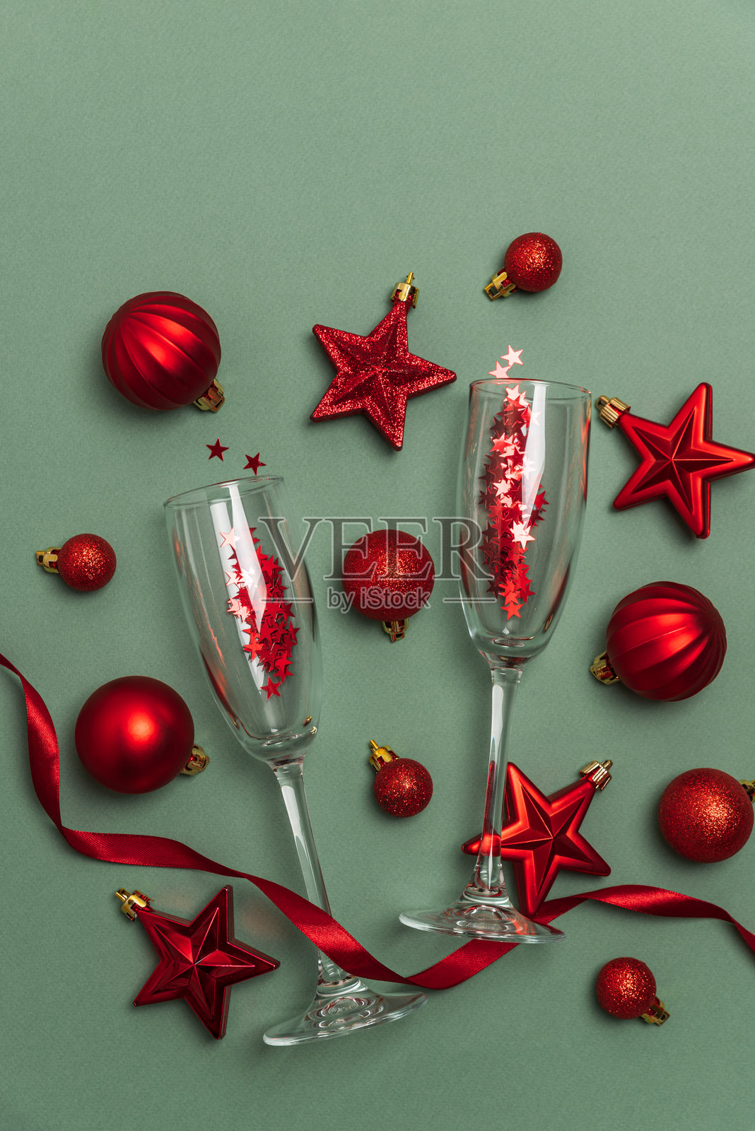 绿色背景上的香槟杯,配有红色圣诞装饰品和丝带照片摄影图片