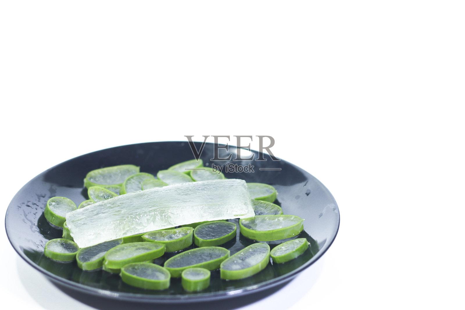 白色背景上黑色盘子里的去皮切片芦荟照片摄影图片
