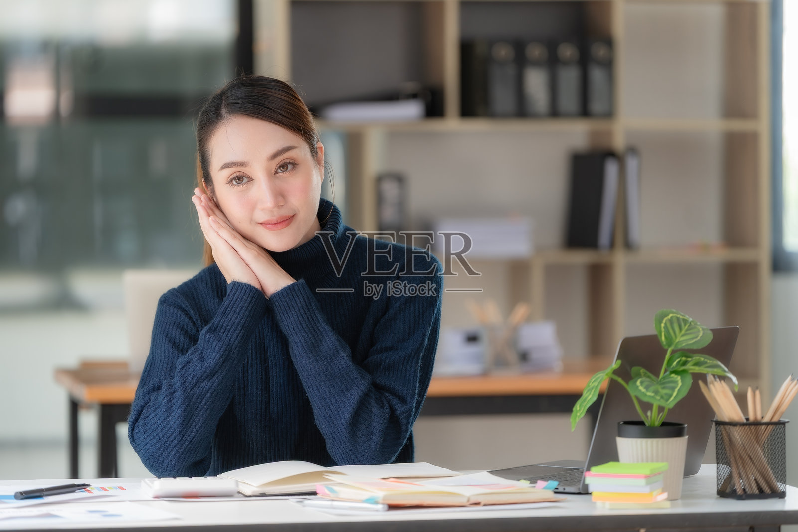 自信的女商人在她的工作区坐着。照片摄影图片