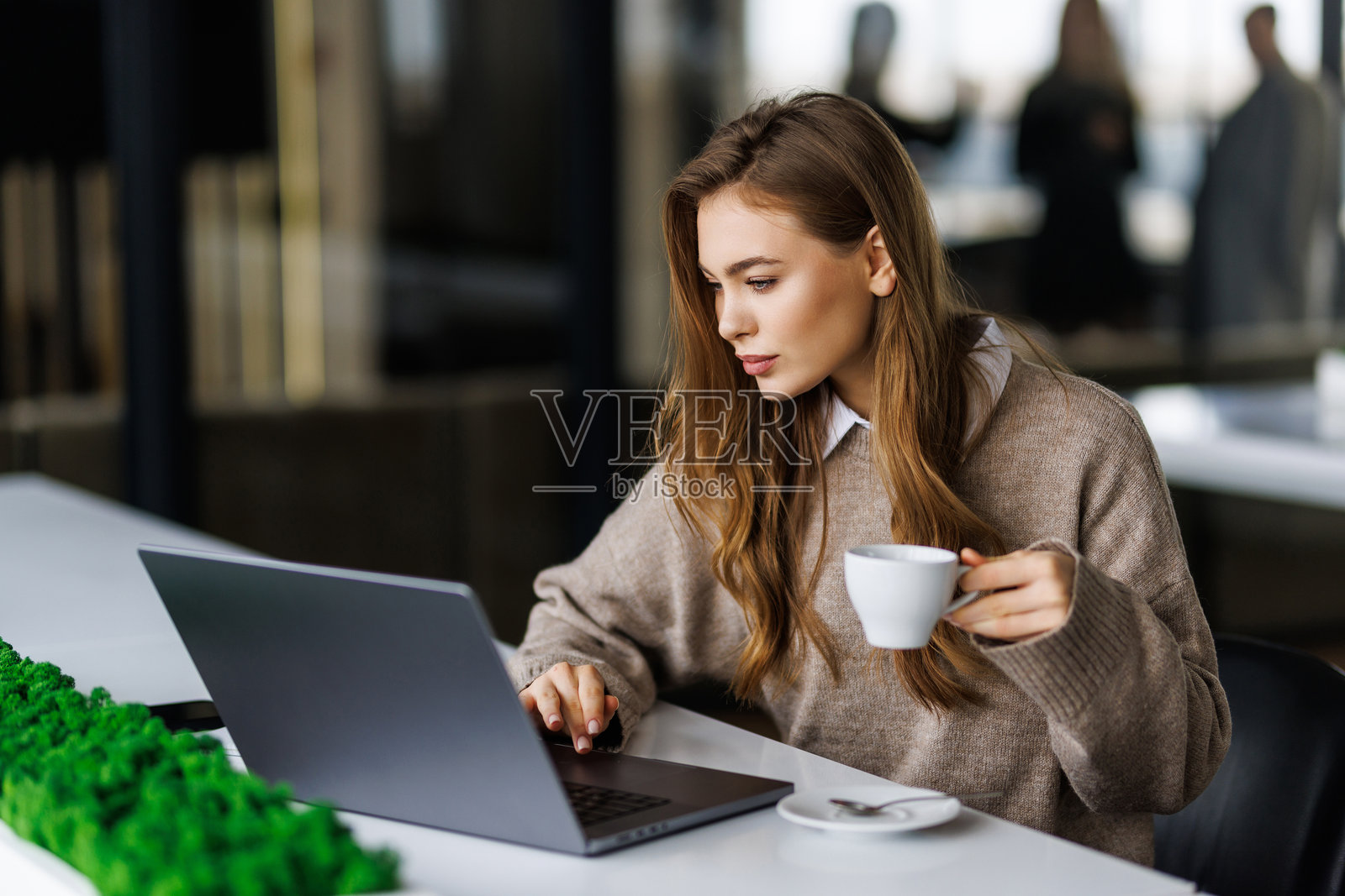 一位快乐的女士在用笔记本电脑工作时享用咖啡照片摄影图片